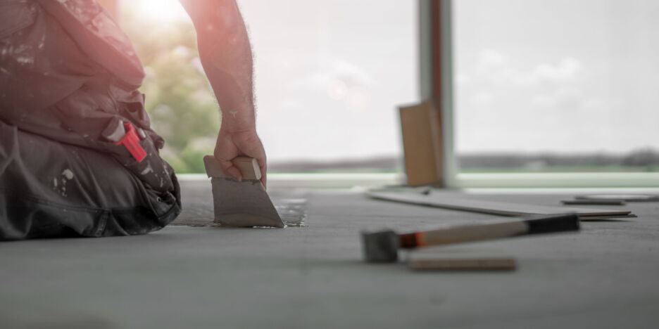 Craftsman puts parquet floor and hits the the bat with the hammer to put the floorboards together